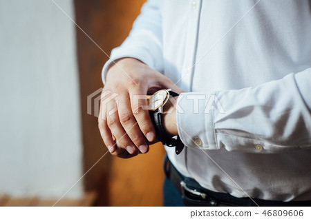 The man in the white shirt in the window wears watches The man in the white shirt in the window wears watches 46809606