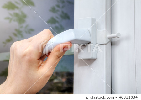 Hands are turning handle of plastic window Hands are turning handle of plastic window 46811034