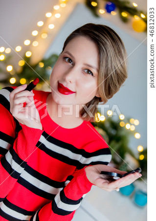 Beautiful woman in red sweater applying lipstick 46812033