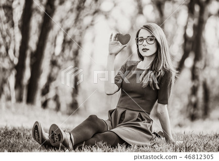 Young woman sitting on a lawn in a park 46812305