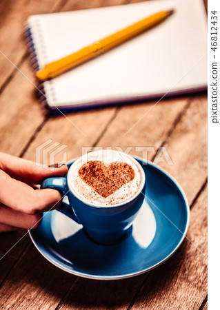 hand holding coffee near notebook and pen 46812434
