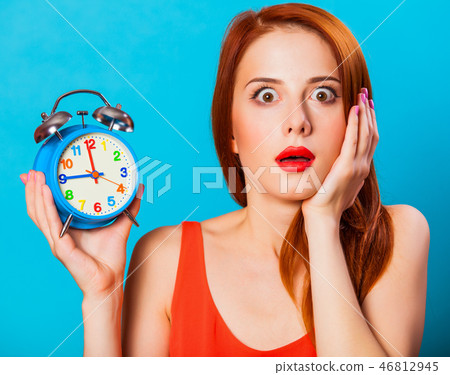 redhead woman woth alarm clock on blue background. redhead woman woth alarm clock on blue background. 46812945