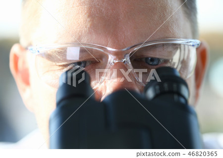 Male scientist looking through binocular Male scientist looking through binocular 46820365