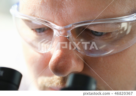 Male scientist looking through binocular Male scientist looking through binocular 46820367