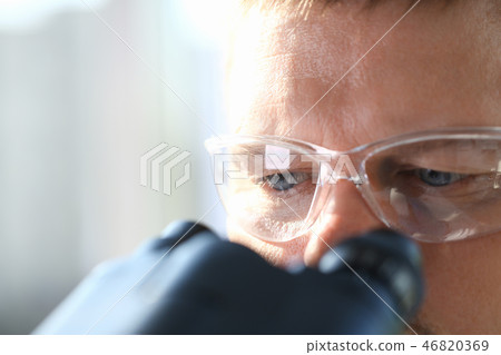 Male scientist looking through binocular Male scientist looking through binocular 46820369
