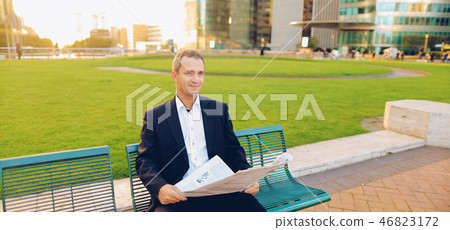 Businessman reading newspaper and looking at watch outside,  . 46823172