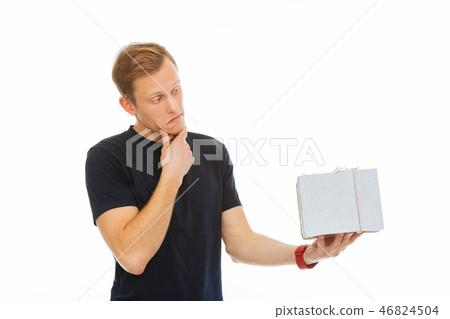 Handsome thoughtful man looking at his present 46824504