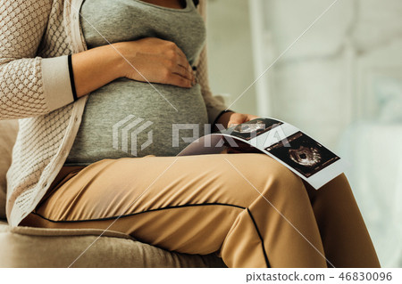 Pregnant belly and the printed ultrasound results 46830096