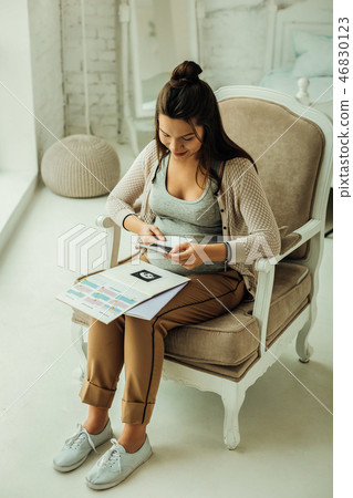 Pregnant woman looking at the ultrasound photo of her future baby 46830123