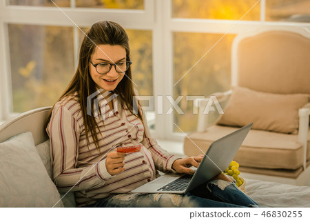 Smiling pregnant woman buying different goods online 46830255