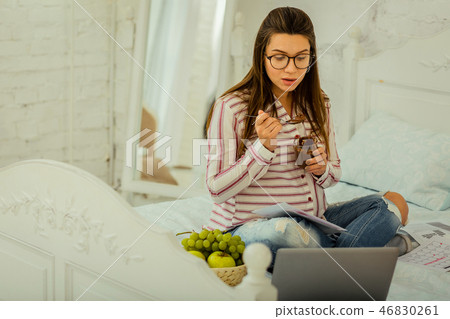 Woman eating chocolate dessert and watching series while pregnancy 46830261
