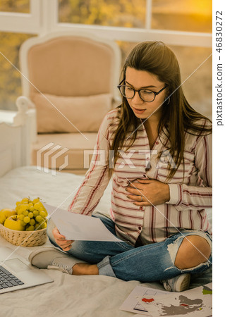 Pregnant woman carefully reading the working paper 46830272