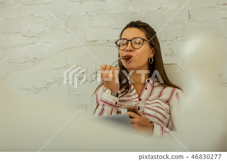 Woman eating a chocolate dessert in her bed Woman eating a chocolate dessert in her bed 46830277