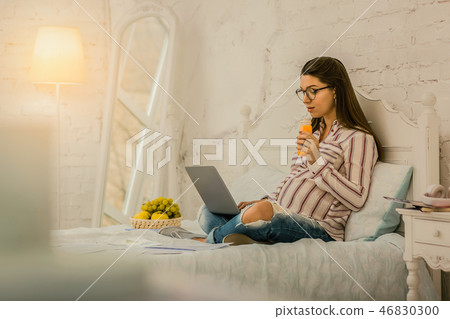 Concentrated pregnant woman working remotely at home 46830300