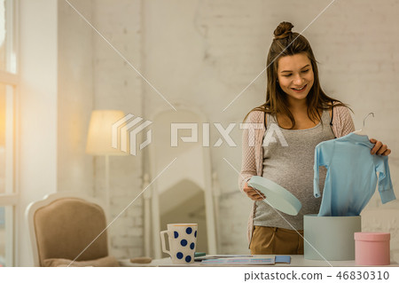 Pregnant woman unpacking the closes for her future baby 46830310