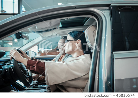 Stylish woman sitting behind the wheel while choosing car Stylish woman sitting behind the wheel while choosing car 46830574