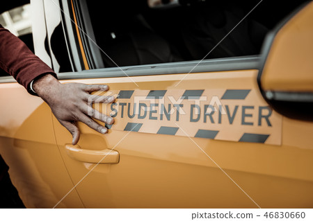 Close up of instructor touching bright orange student driver car Close up of instructor touching bright orange student driver car 46830660