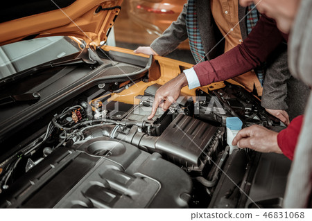 Top view of car salon representative telling his clients about engine Top view of car salon representative telling his clients about engine 46831068