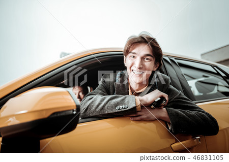 Cheerful student smiling broadly while sitting in his new car Cheerful student smiling broadly while sitting in his new car 46831105