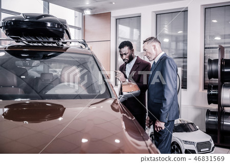 Consultant standing near big passenger car with his client Consultant standing near big passenger car with his client 46831569