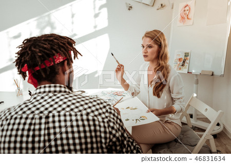 Artist holding painting brush while teaching her student 46831634