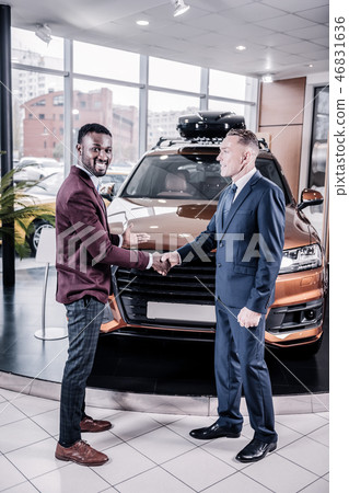 African-American representative of car salon smiling after successful deal African-American representative of car salon smiling after successful deal 46831636