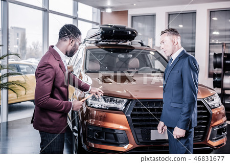 Professional car consultant wearing dark red jacket assisting client Professional car consultant wearing dark red jacket assisting client 46831677