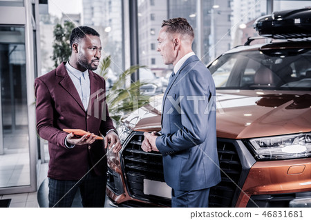 Handsome businessman wearing dark costume buying new car Handsome businessman wearing dark costume buying new car 46831681