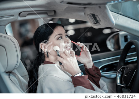 Busy stylish businesswoman fixing her makeup sitting in traffic jam Busy stylish businesswoman fixing her makeup sitting in traffic jam 46831724