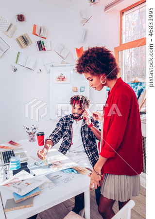 Stylish designer wearing red jacket standing near her colleague Stylish designer wearing red jacket standing near her colleague 46831995