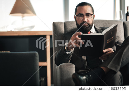 Bearded man wearing glasses and hand watch holding the Bible Bearded man wearing glasses and hand watch holding the Bible 46832395