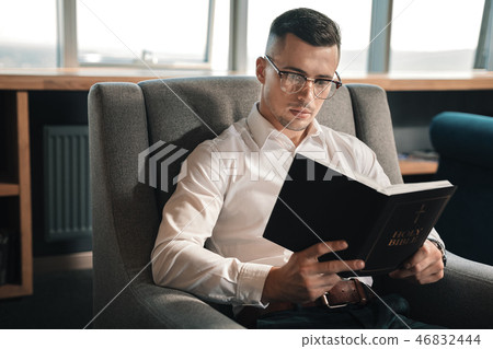 Young man believing in fate reading the Bible on weekend 46832444