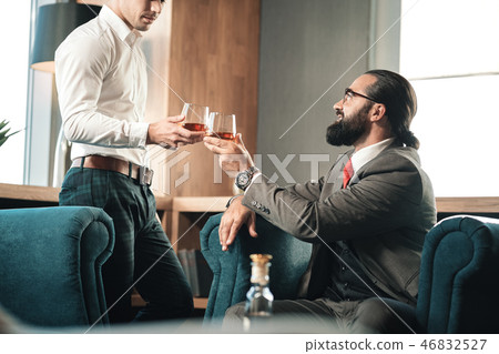 Young employee joining his boss in the restaurant drinking whisky Young employee joining his boss in the restaurant drinking whisky 46832527