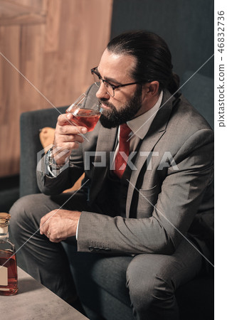 Top view of businessman sitting on sofa and drinking cognac Top view of businessman sitting on sofa and drinking cognac 46832736