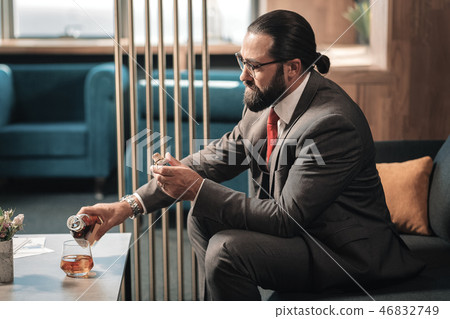Bearded businessman pouring some cognac into the glass 46832749