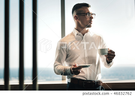 Businessman standing near the window enjoying sunny day Businessman standing near the window enjoying sunny day 46832762