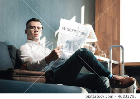 Stylish businessman reading news while sitting in hotel lobby 46832783
