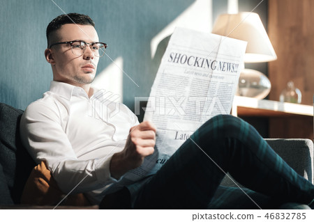 Young handsome man wearing glasses reading shocking news 46832785
