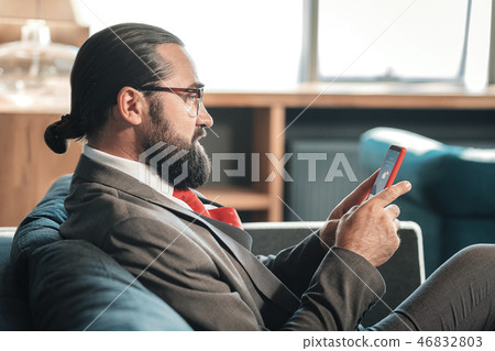 Businessman wearing glasses checking weather forecast on his phone Businessman wearing glasses checking weather forecast on his phone 46832803