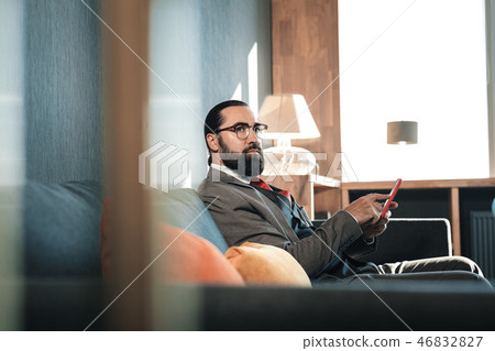 Dark-eyed mature man waiting for his business partner sitting on sofa 46832827