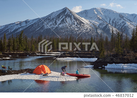 Couple man and woman in a camp at mountain terrain. Lake shore with canoe Couple man and woman in a camp at mountain terrain. Lake shore with canoe 46837012