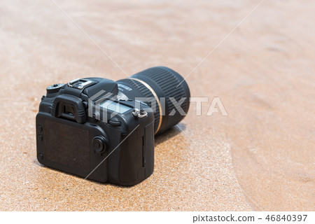 DSLR camera on beach wet from water sea wave DSLR camera on beach wet from water sea wave 46840397