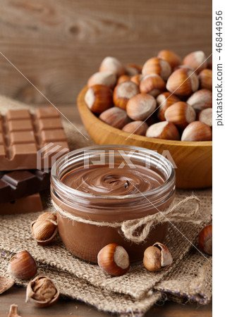 Chocolate spread with hazelnuts on wooden background Chocolate spread with hazelnuts on wooden background 46844956