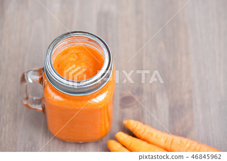 Healthy carrot smoothie in a jar with tube on wooden background 46845962