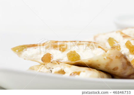 Pancakes stuffed with cottage cheese and raisins. 46846733