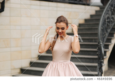 Model with brunette hair in a powder color dress and with evening makeup 46849896