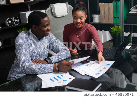 two young black people discuss their business using diagrams sitting at Desk in the office 46850071