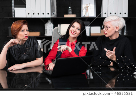 Three female colleagues sitting in office at table with laptop 46855581
