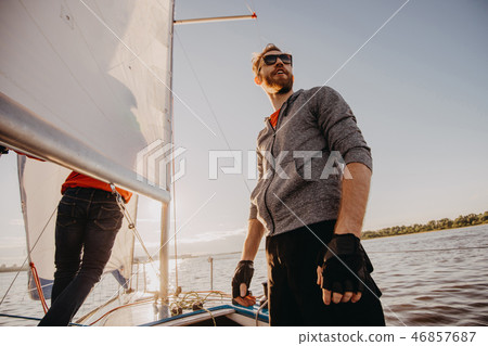 Successful young bearded man sailing portrait at sunrise on boat 46857687