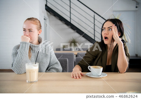 Two upset international girls offended at each other sadly looking aside spending time together in 46862624